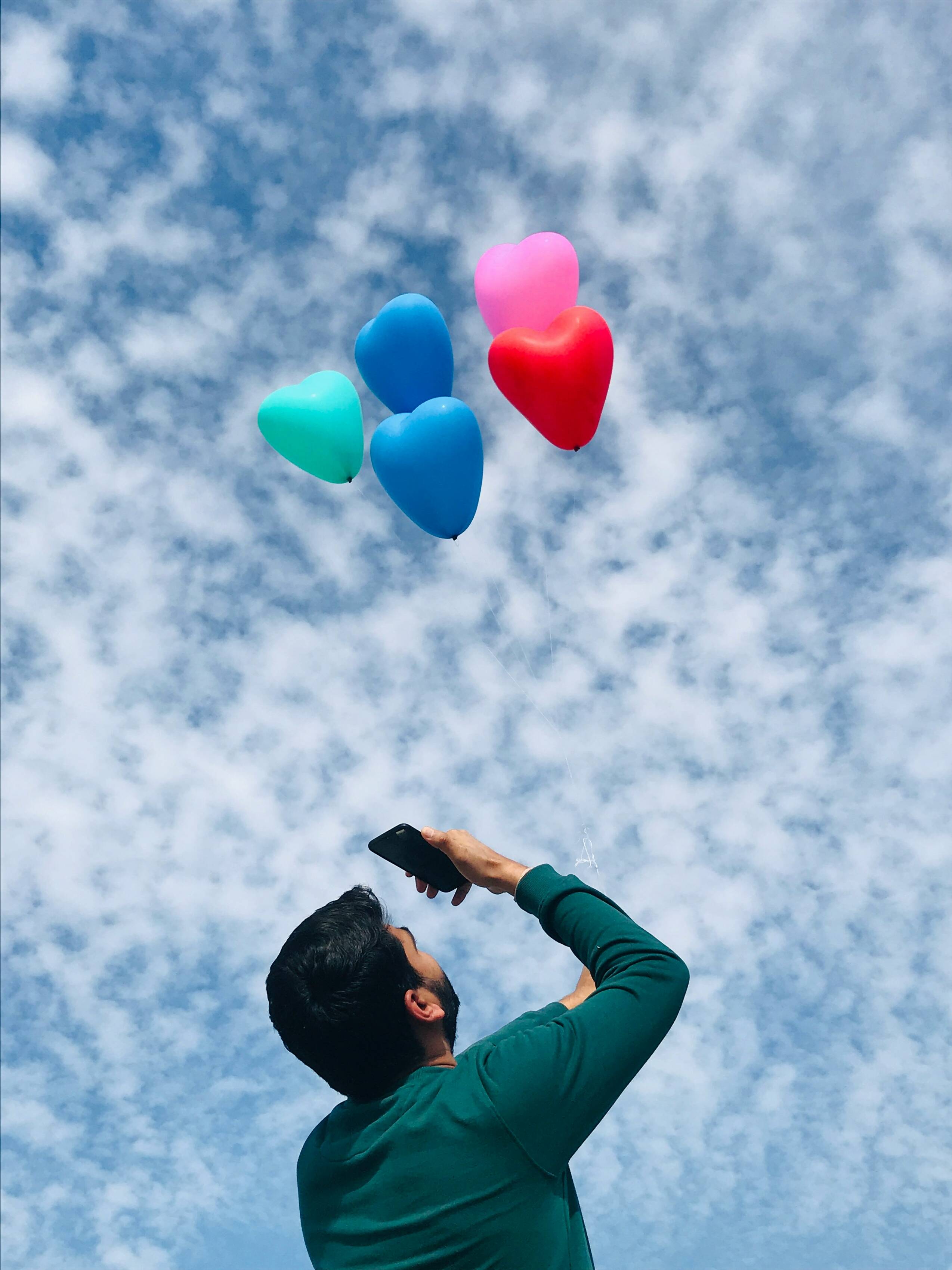 Man click heart-shaped balloon pictures from mobile. 